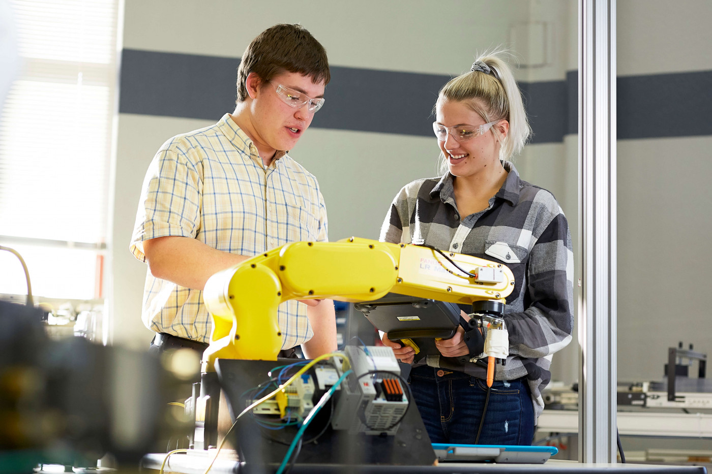 Manufacturing Operations Manager working with staff on robotic arm