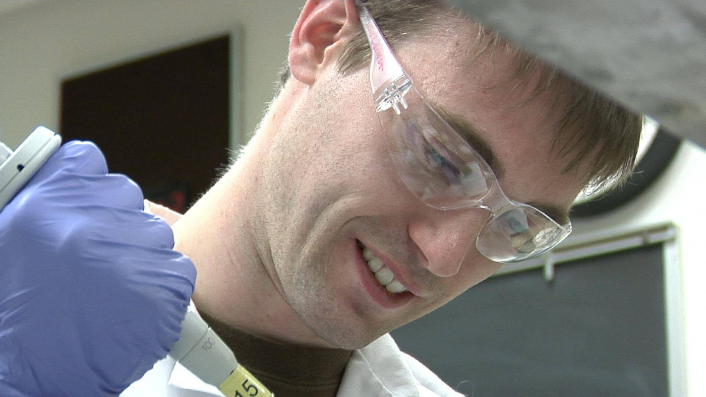 Lab assistant with safety glasses and a syringe