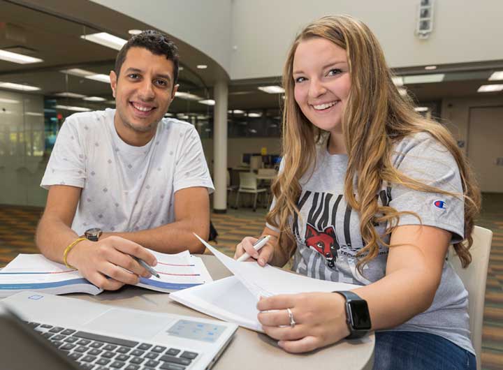 Two students studying together and smiling