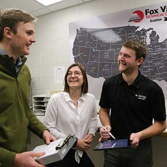 Three people laughing in a classroom