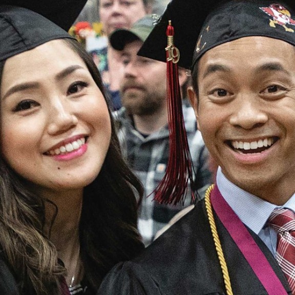 Two graduates smiling together at graduation ceremony