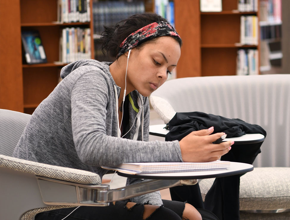 Student with headphones studying at campus library