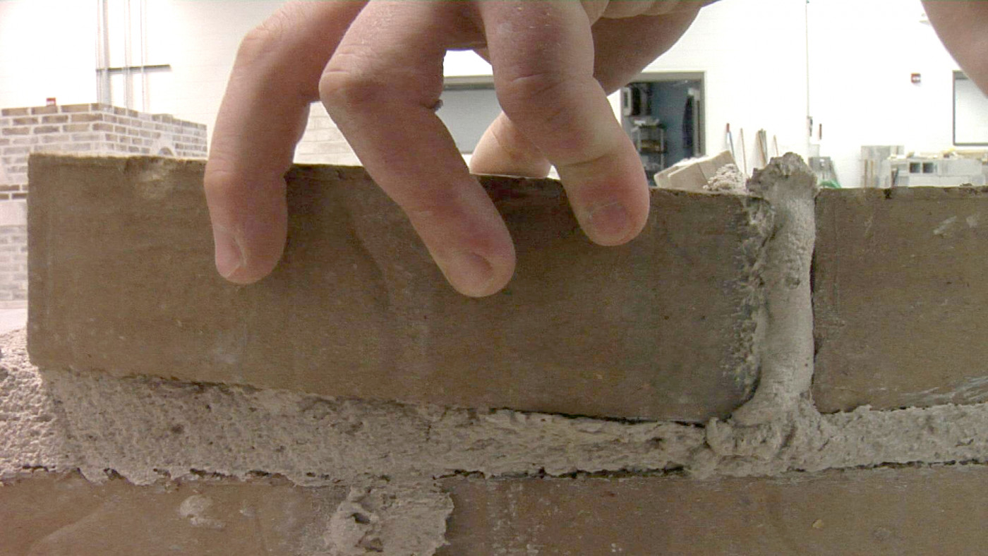Student laying a wall of bricks